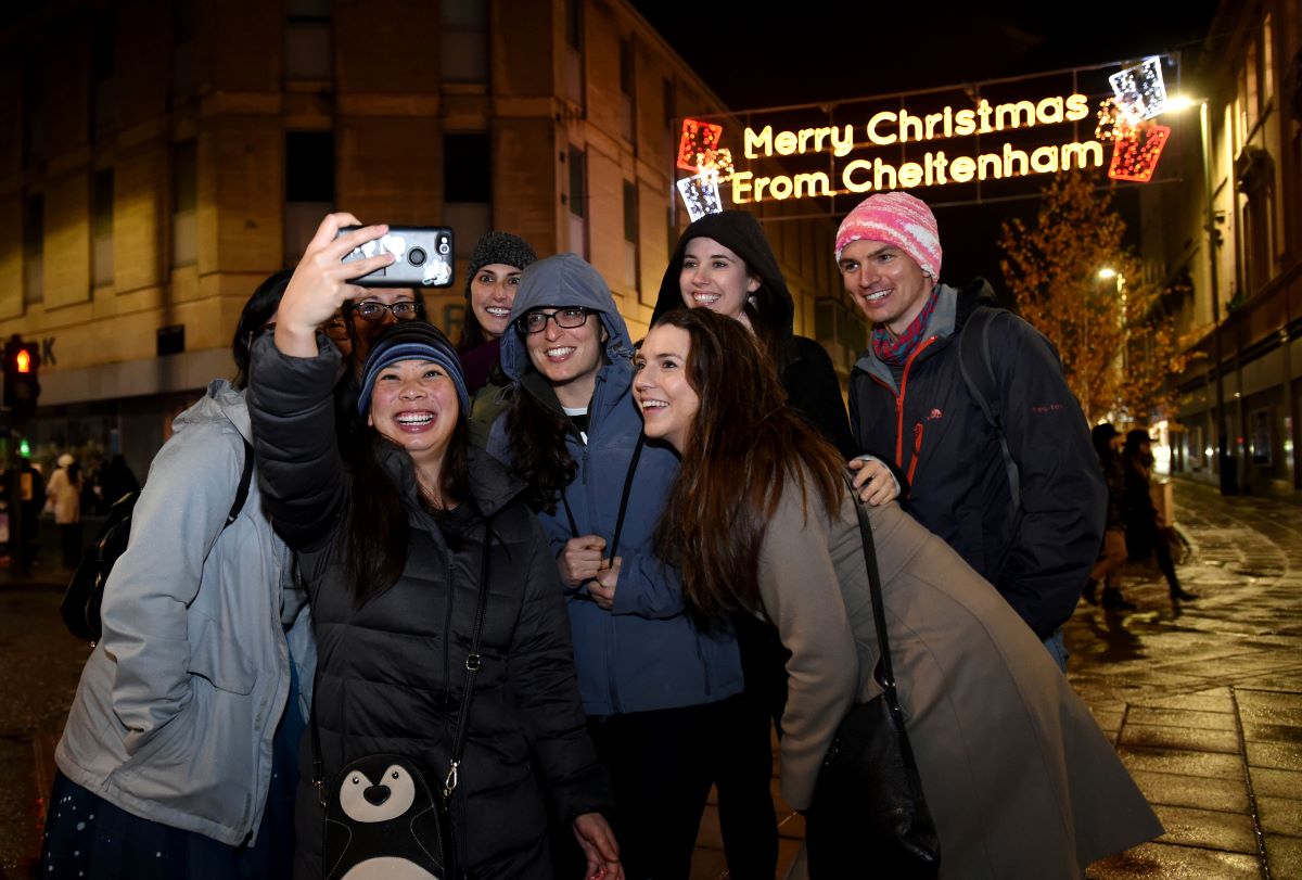 Spectators taking selfie in front of giant illuminated Merry Christmas sign